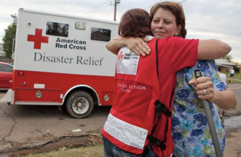 A woman volunteering and hugging another woman.